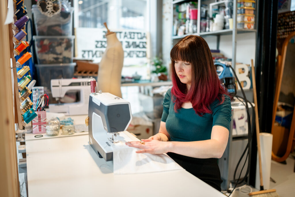 Claire Couchman sewing at a machine in her London studio using reclaimed fabrics.